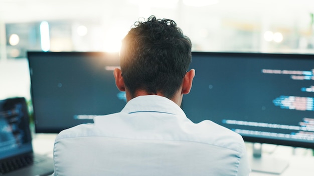 Programmer man and computer screen with reading in office for writing code planning digital software and debugging Back programming and employee with data analytics for app development or testing
