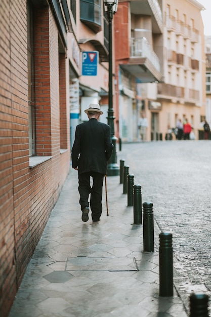 Rear view of man walking on footpath in city