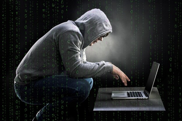 Sandalyede çömelmiş ve bir dizüstü bilgisayara bakan adamla birlikte ikili kod, çılgın bir programcı konsepti