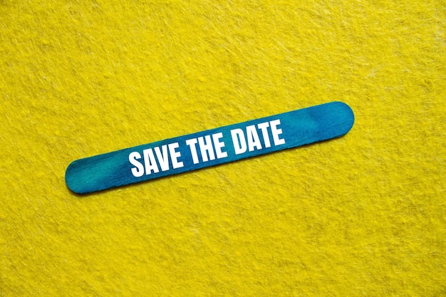 Save the date message written on blue wooden stick with yellow background Conceptual save the date symbol Copy space