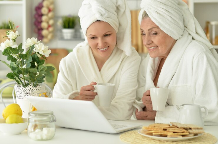 Fotoğraf senior woman and  daughter  in a bathrobe with laptop and tea