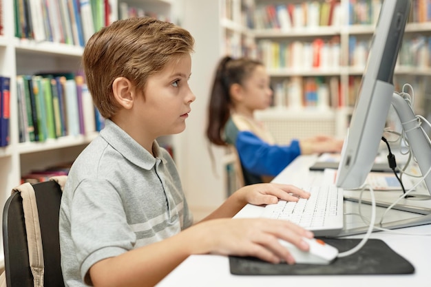 serious boy using pc in programming class for kids
