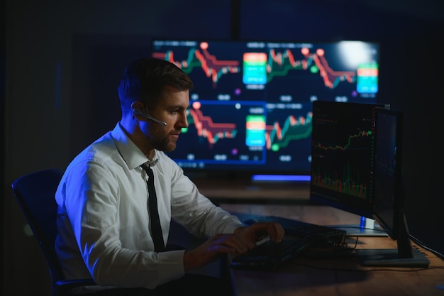Side view of crypto broker sitting at office table analyzing market looking at screen