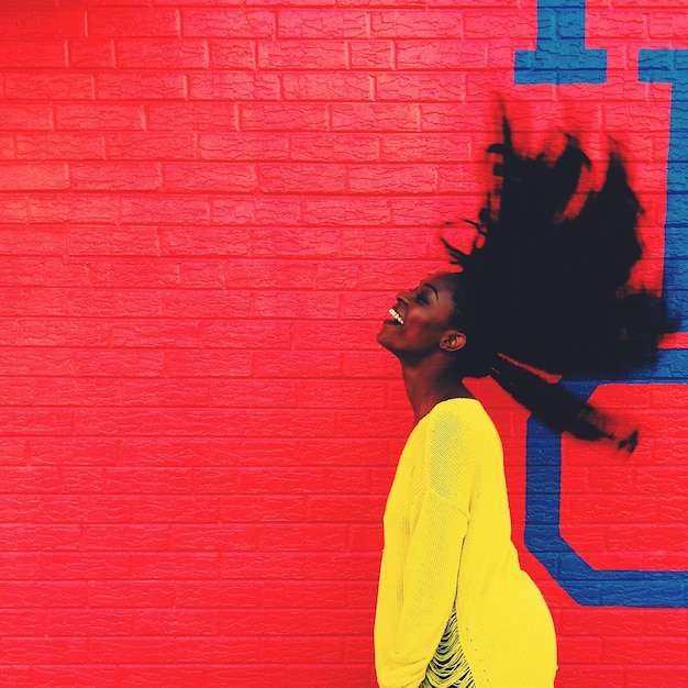 Side view of young woman with tousled hair graffiti wall