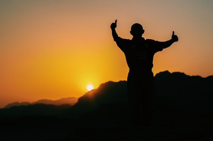 Fotoğraf silhouette man with arms raised against sky during sunset