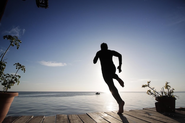 silhouette of man jumping in the sea