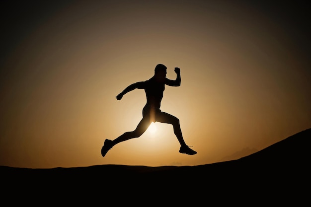 Silhouette of running man on sunset fiery sky background in mountain, sport and recreation, future and success, people and nature, speed and healthy lifestyle