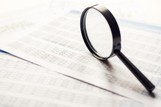 Single Magnifying Glass with Black Handlestaying on the financial data Business and Finance concept