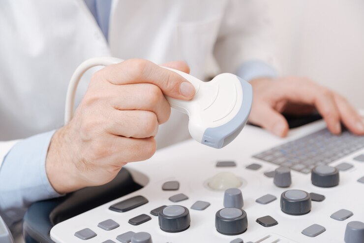 Fotoğraf skilled talented involved practitioner working in the hospital and using ultrasound linear transducer while checking sonogram equipment