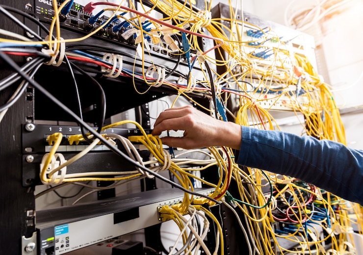 Fotoğraf sunucu odasında çalışan ağ mühendisi. ağ kablolarını switch’lere bağlıyor