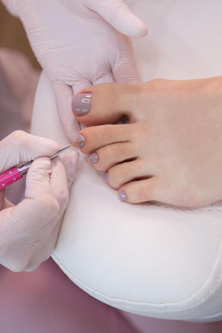 Fotoğraf the pedicure master applies gel polish to the nails with a brush