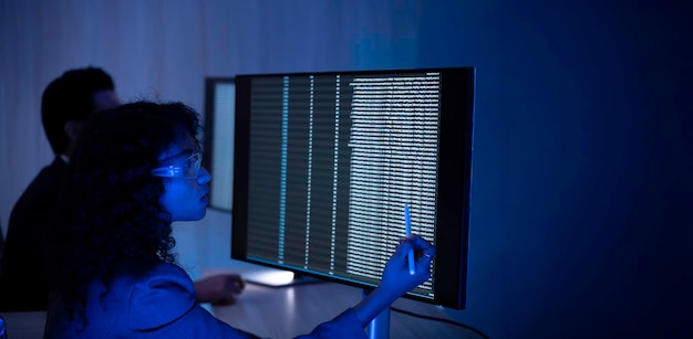 Two software developers collaborating at night focusing on code review and debugging process on a computer screen representing teamwork innovation and modern software development workflow