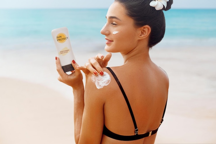 Fotoğraf woman apply sun cream protection cream on her tanned shoulder beautiful girl on a beach