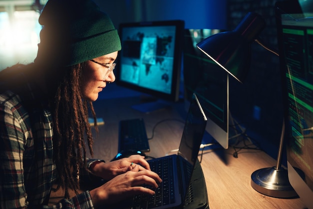 woman laptop and hacker typing in home with software data programming or cybersecurity developer it coder and female focus on hacking phishing or malware code on computer for dark web at night