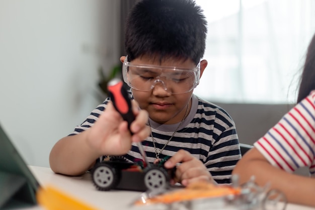 young asia student remotely learn online at home in coding robot car and electronic board cable in stem steam mathematics engineer science technology computer code in robotics for kids