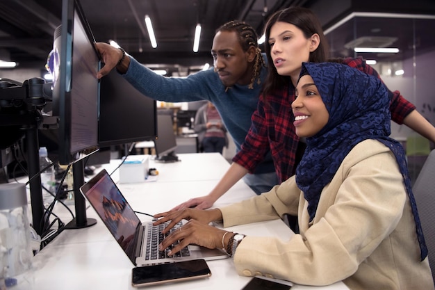 young multiethnics business team of software developers working together using laptop computer while writing programming code at modern startup office