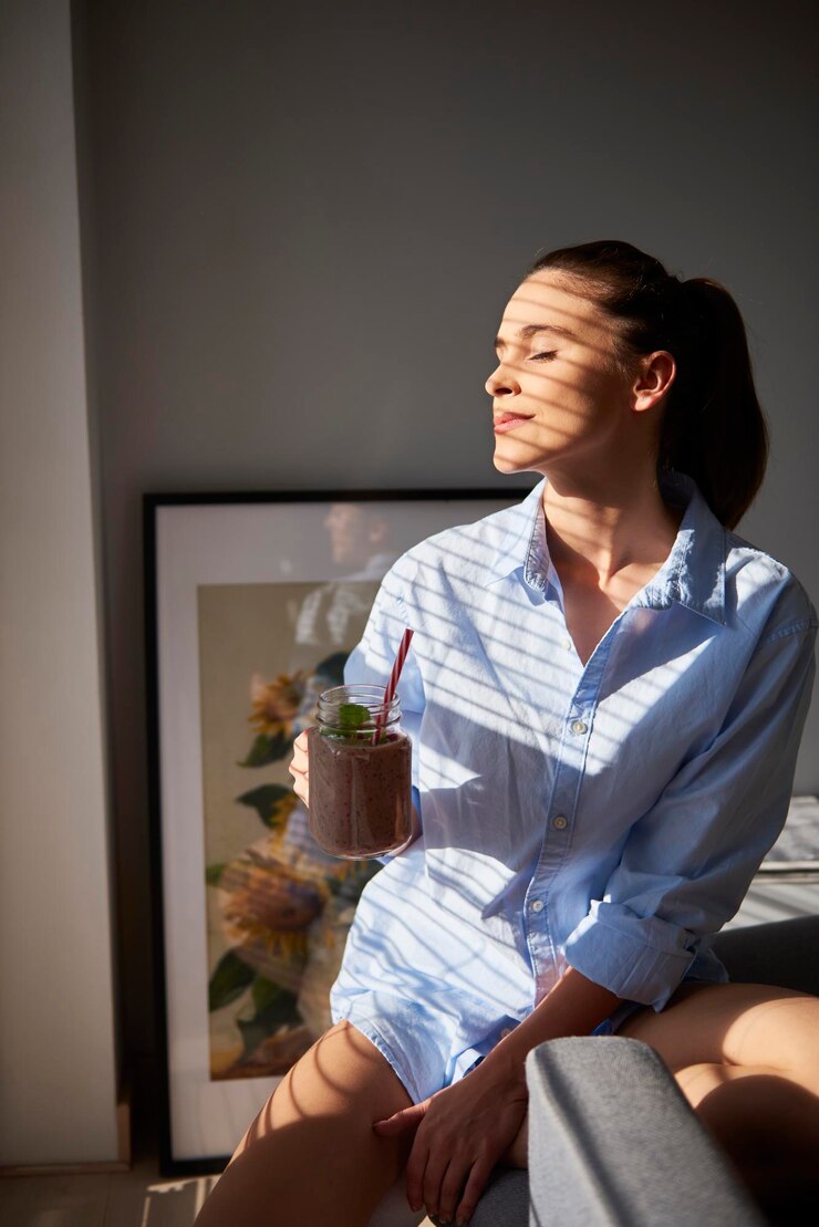 Fotoğraf young woman drinking smoothie at home