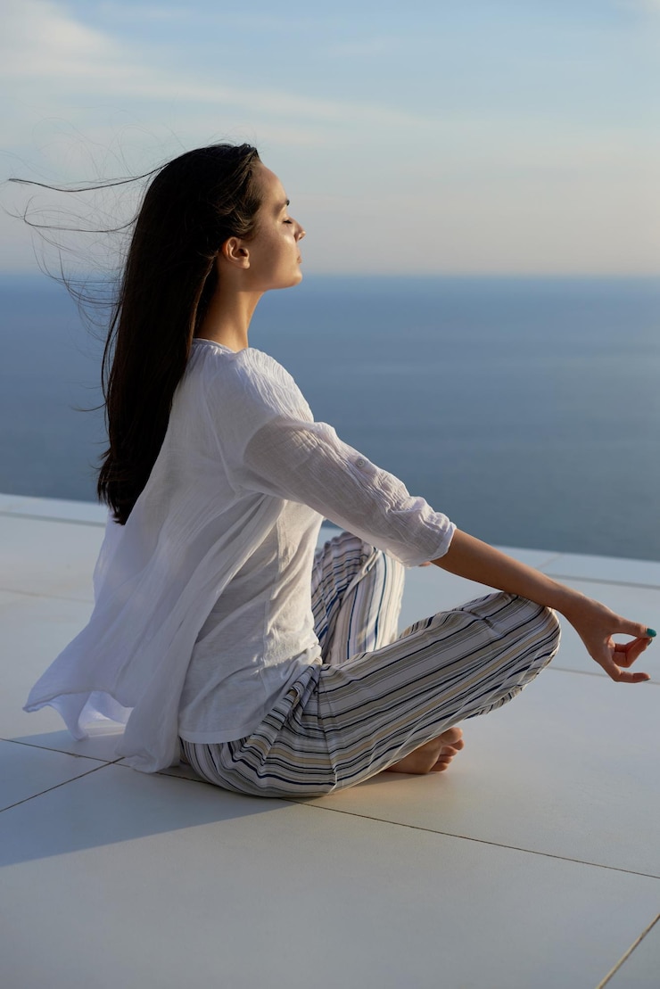 Fotoğraf young woman practice yoga meditaion on sunset with ocean view in background