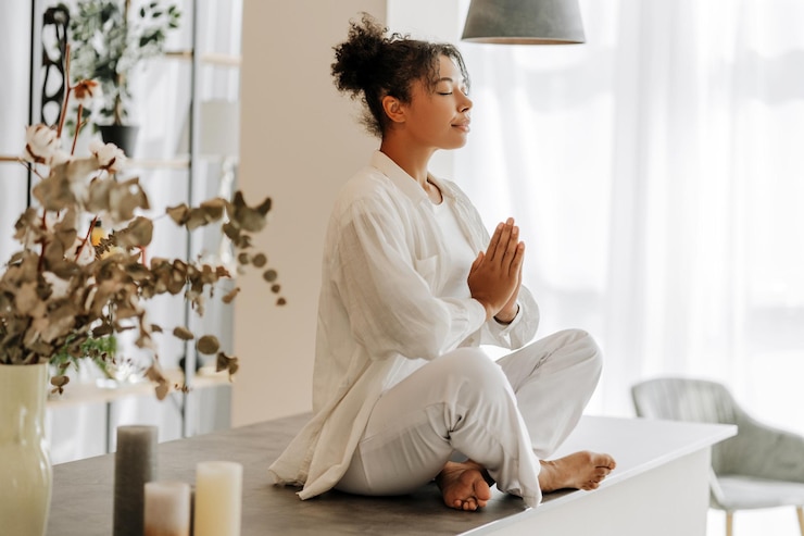 Fotoğraf young woman practicing yoga meditation at home on a table