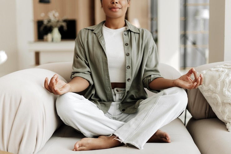 Fotoğraf young woman practicing yoga meditation at home sitting on sofa
