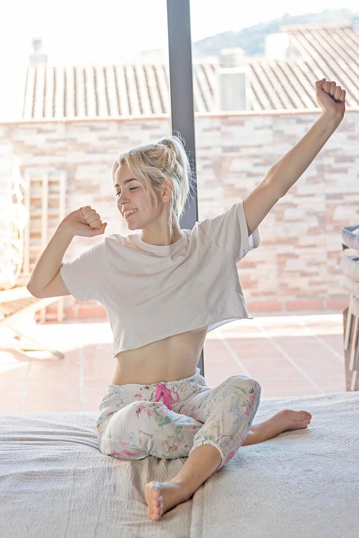 Fotoğraf young woman with eyes closed sitting on bed at home