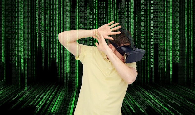 3d technology, virtual reality, entertainment and people concept - scared young man with virtual reality headset or 3d glasses playing game and covering from something over binary code background