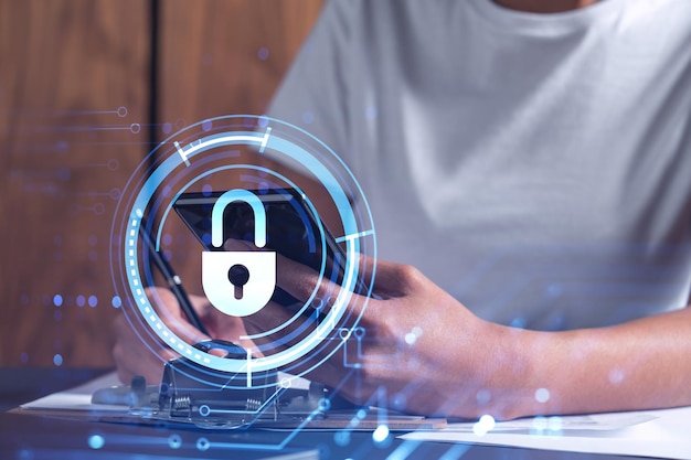 A businesswoman in casual wear signing the contract to prevent probability of risks in cyber security Checking the phone Padlock Hologram icons over the working desk Women in business concept