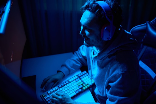 A coder is working late at night on a computer screen coding and using a smartphone app