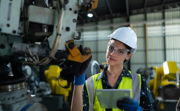 A female engineer installs a program on a robotics arm in a robot warehouse And test the operation before sending the machine to the customer