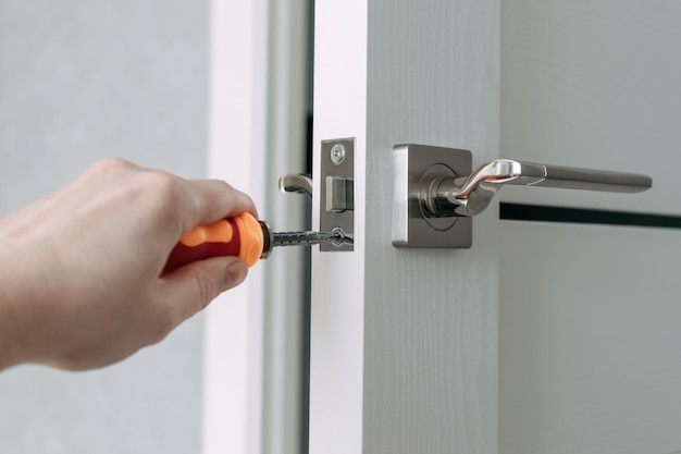 A handyman repair the door lock in the room The concept repair yourself Selective focus