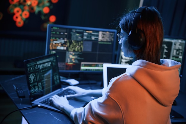 A lot of information on displays Young professional female hacker is indoors by computer