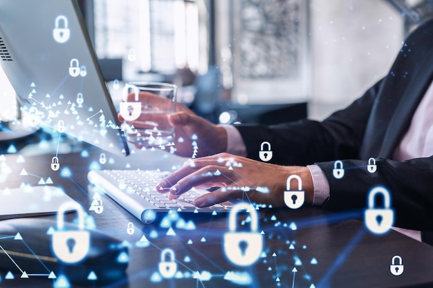 A programmer is typing a code on computer to protect a cyber security from hacker attacks and save clients confidential data Padlock Hologram icons over the typing hands Formal wear