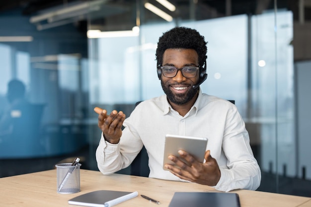 A support worker with a headset looks into the camera a man holds a tablet computer in his hands