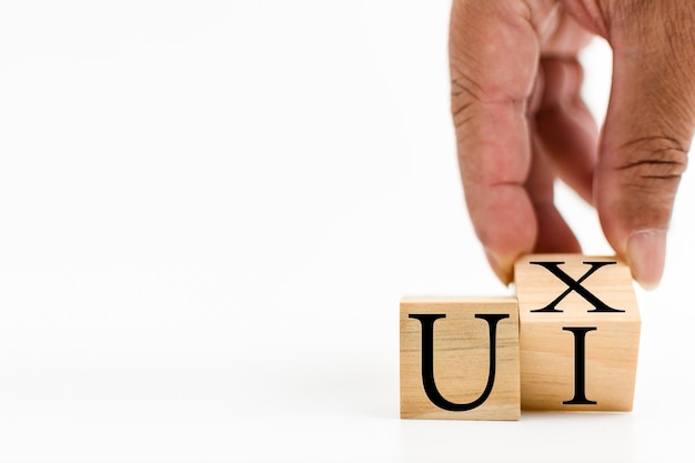A wooden cube on a white table with text UI UX Concept of development and design and development user interface user experience software app Copy space on left for a design White background