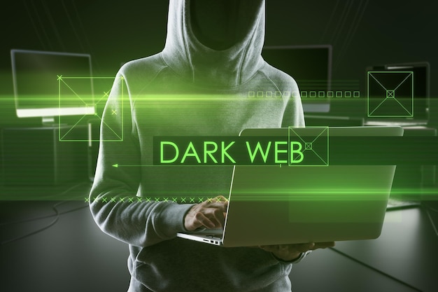 Abstract dark web text over hacker holding and using laptop computer on blurry background Hacking and attack concept Double exposure