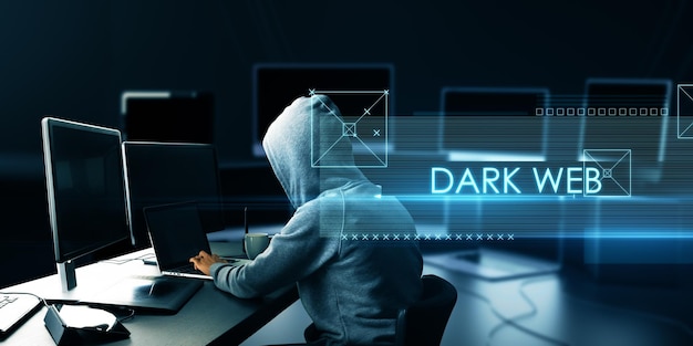 Abstract dark web text over side view of hacker at desk using computers on blurry background Hacking malware and attack concept Double exposure