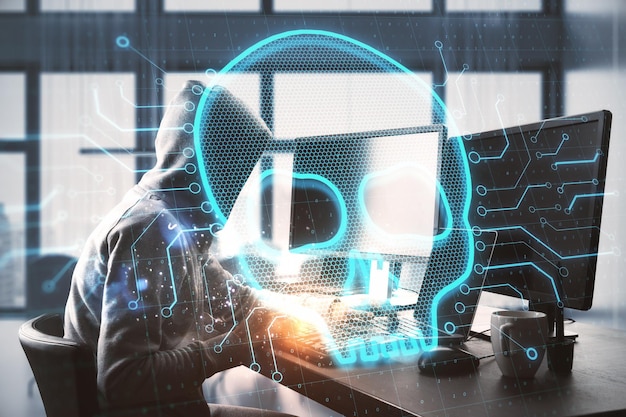 Abstract image of hacker at desktop using computers with glowing digital skull on blurry background Hacker technology cyber and virus concept Double exposure