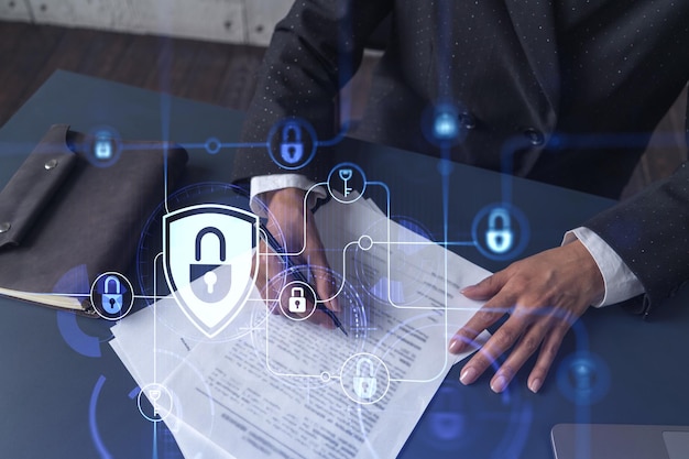 African American businesswoman in formal wear signing the contract to prevent probability of risks in cyber security Padlock Hologram icons over the working desk Women in business concept