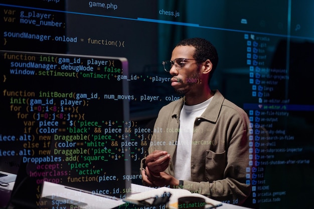 African American Coder Analyzing Complex Code on Screen