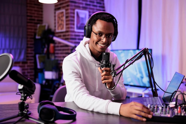 African american internet star recording show on camera, using sound equipment in studio. Portrait of smiling content creator talking to audience looking at camera and filming live broadcast