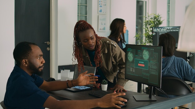 African american team of engineers working on server development with html script and terminal window. Computers being hacked and developers having no access in agency system network.