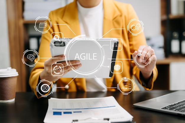Agile development methodology concept Business hand using laptop computer and tablet with virtual screen Agile icon on modern office digital technology concept