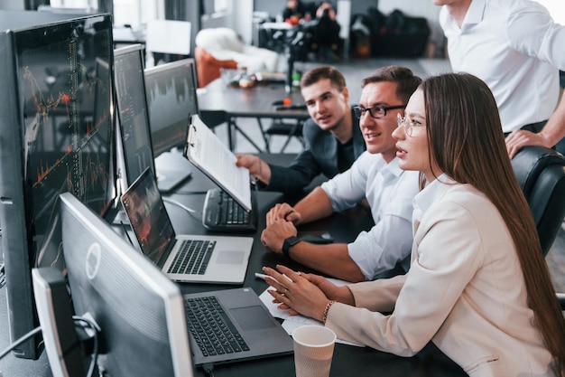 Analysing information Team of stockbrokers works in modern office with many display screens