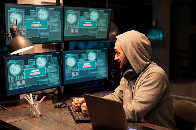 Angry mad hacker punching keyboard after failing to hack computer system, trying to break into company database to steal information. Aggressive man throwing fists and doing cyber attack.