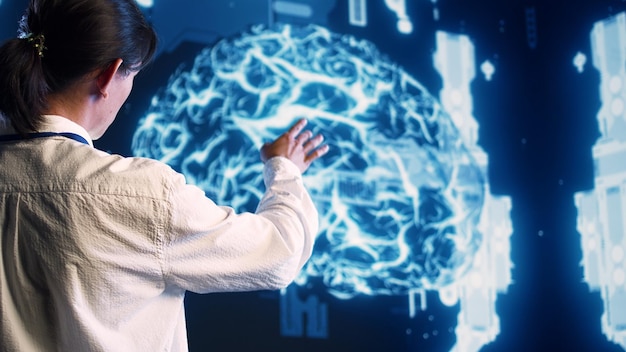 Asian developer looking at hologram of artificial intelligence cognitive computing human brain simulation. Programmer interacting with AI visualization showing machine learning algorithms