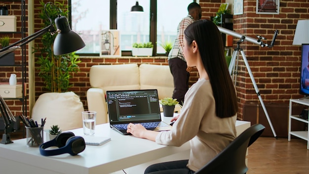 Asian freelancer woman works on programming code in a modern office