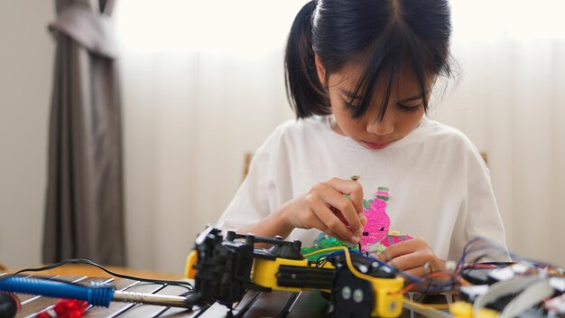 asian girl assembling robot parts at home learning stem and electronics developing engineering skills logical thinking and problemsolving through handson coding education for kids