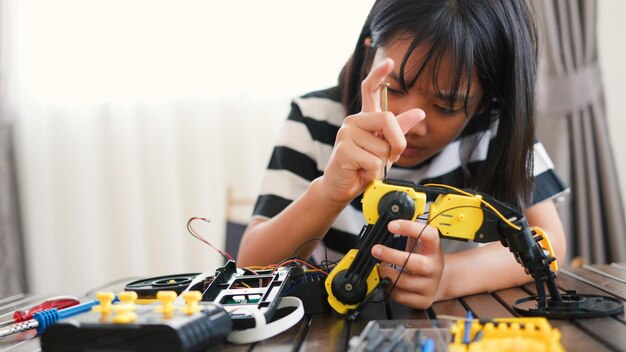 asian girl assembling robotic arm at home promoting stem education coding engineering and problemsolving skills handson tech learning for future innovators and young engineers
