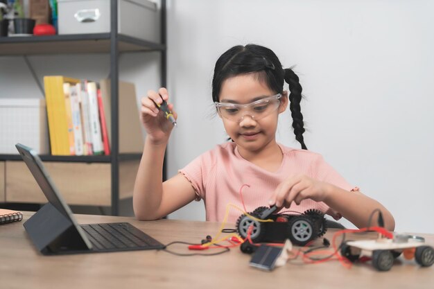 Asian littlle girl constructing and coding robot at STEM classFixing and repair mechanic toy car
