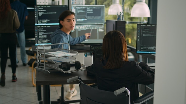 Asian software developer with impairment writing code with html script in data room. System engineer programming user interface in artificial intelligence developing agency, disability friendly.